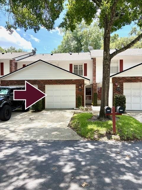 A two-story townhouse with a brick facade, white garage door, and a parked black truck — 5171 LAZY OAKS DRIVE, WINTER PARK, FL