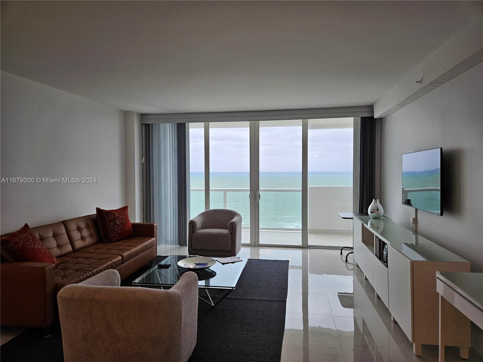 A living room features a leather sofa, two armchairs, a glass coffee table, and ocean views — 5601 Collins Ave # 1605, Miami Beach FL 33140, MIAMI BEACH, FL