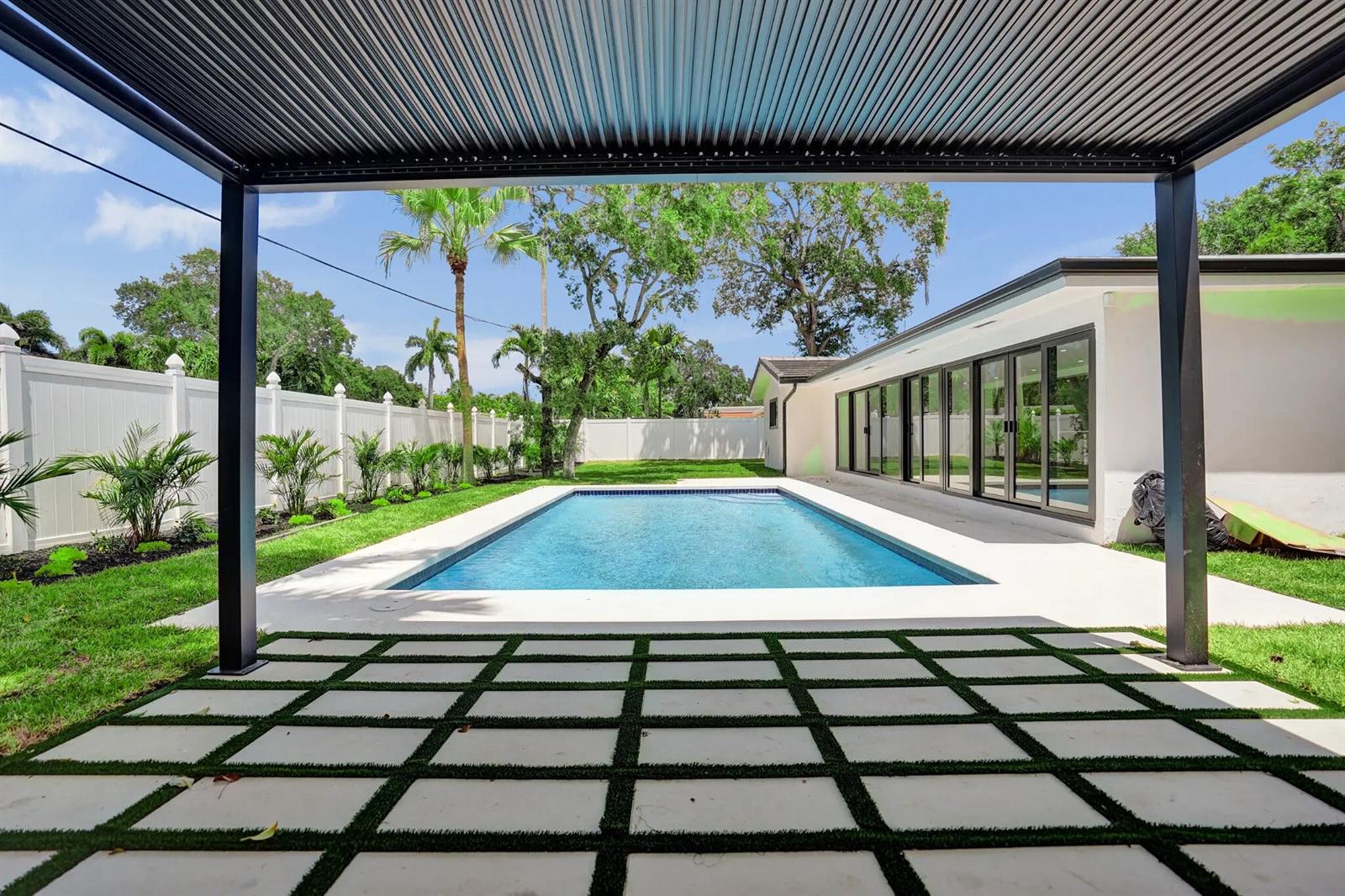 A backyard features a rectangular swimming pool, a white fence, and a covered patio area — 669 SW 3rd Street, Boca Raton FL 33486, BOCA RATON, FL