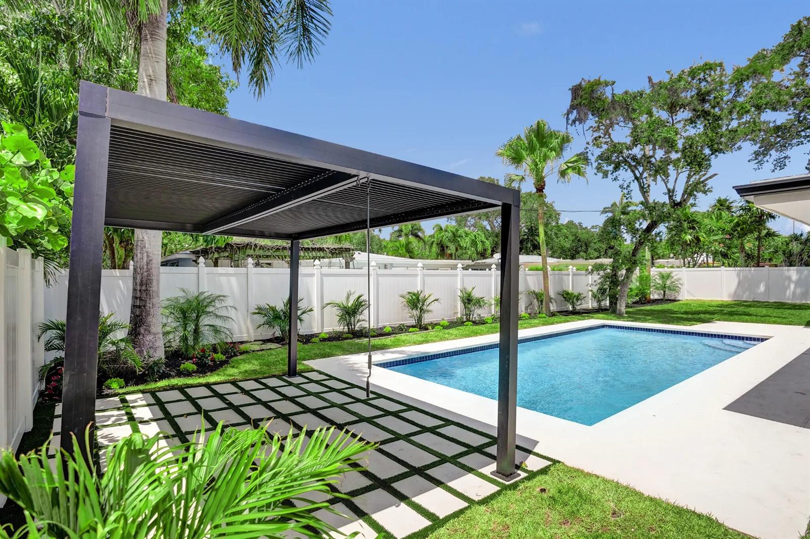 A backyard features a swimming pool, a modern louvered pergola, and a grid-patterned patio — 669 SW 3rd Street, Boca Raton FL 33486, BOCA RATON, FL