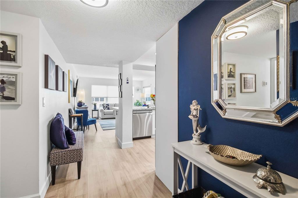 A hallway with a blue accent wall leads into a living room and kitchen area — 3804 GULF OF MEXICO DRIVE UNIT B204, LONGBOAT KEY, FL