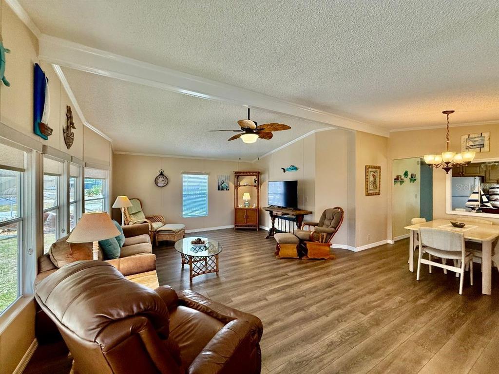 A living room and dining area feature wood-look flooring, beige walls, and a ceiling fan — 1415 BLUE HERON DRIVE, ENGLEWOOD, FL