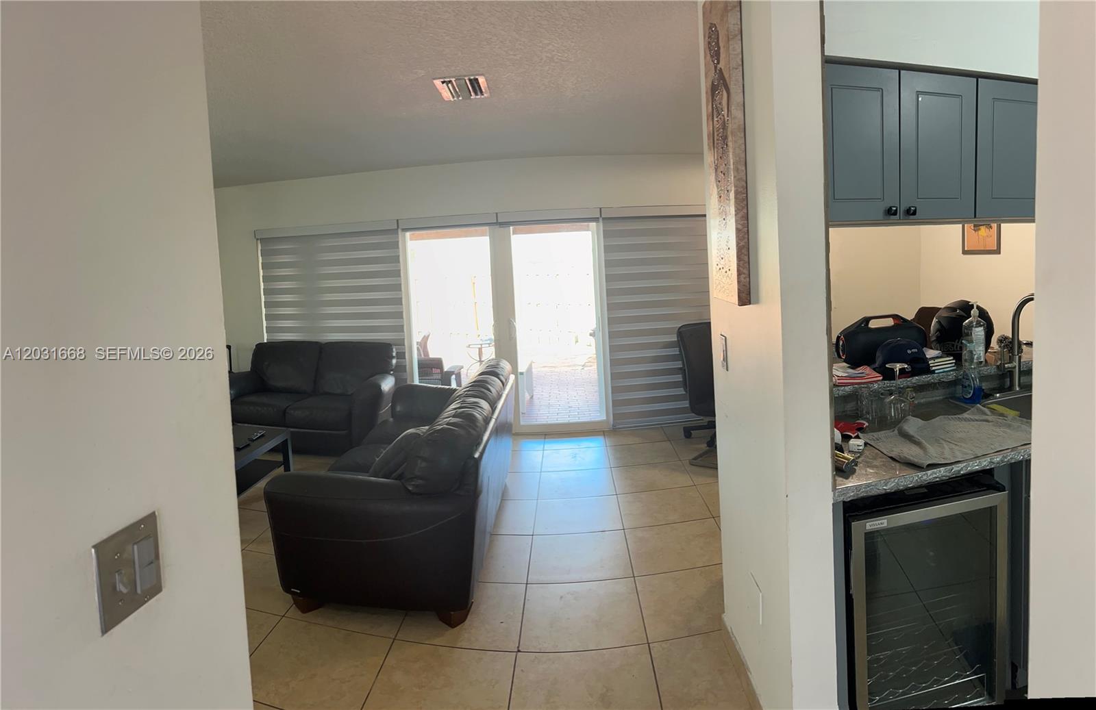 A living room with dark leather sofas leads to a patio through sliding glass doors — 9206 SW 147th Ct, Miami FL 33196, MIAMI, FL