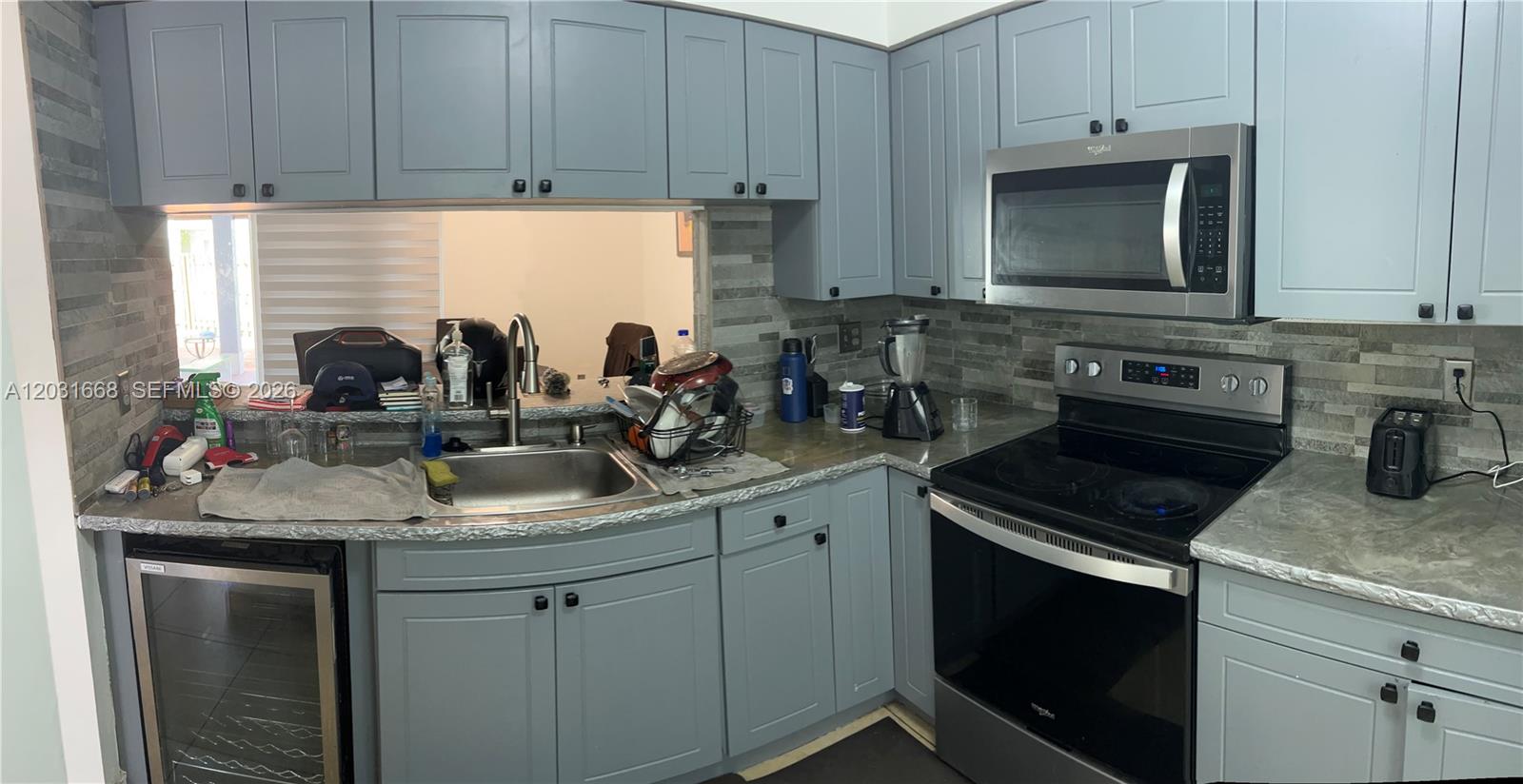 A kitchen features blue cabinets, stainless steel appliances, and a gray stone-tiled backsplash — 9206 SW 147th Ct, Miami FL 33196, MIAMI, FL