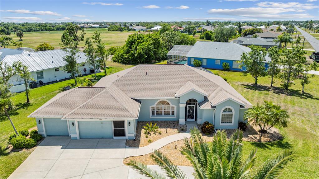 An aerial view of a light blue single-story house with a shingled roof and driveway — 54 MEDALIST PLACE, ROTONDA WEST, FL
