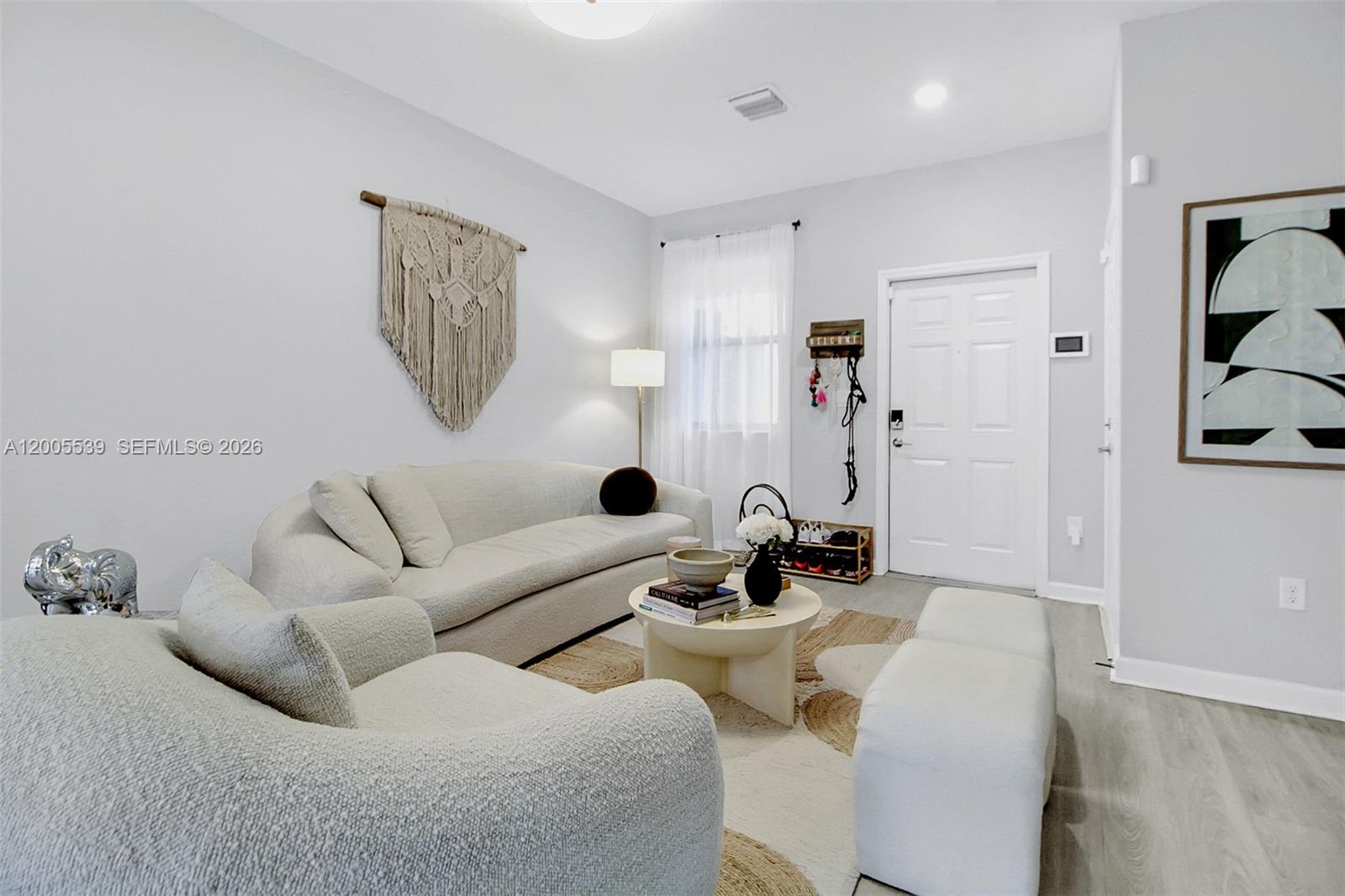 A living room features a curved sofa, armchairs, a coffee table, and wall decor — 12766 SW 229th Ter, Miami FL 33170, MIAMI, FL