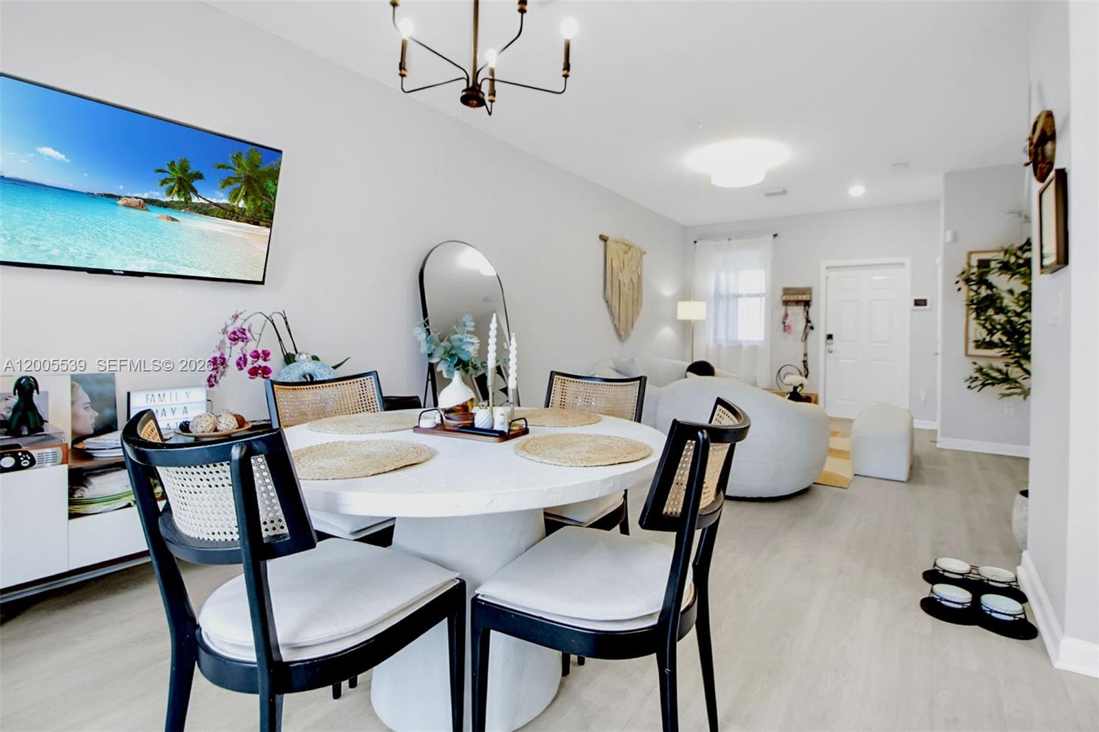 A dining area with a round white table and black chairs sits before a living room — 12766 SW 229th Ter, Miami FL 33170, MIAMI, FL