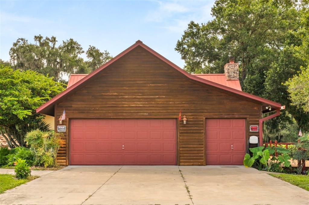 A house with a red metal roof sits beside a large stone-lined swimming pool — 35841 TIMBERTOP LANE, FRUITLAND PARK, FL