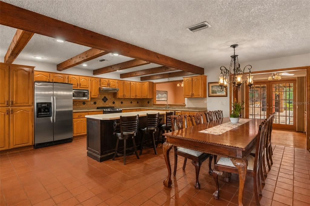 A living room features a stone fireplace, vaulted wood ceilings, and large windows overlooking fields — 35841 TIMBERTOP LANE, FRUITLAND PARK, FL