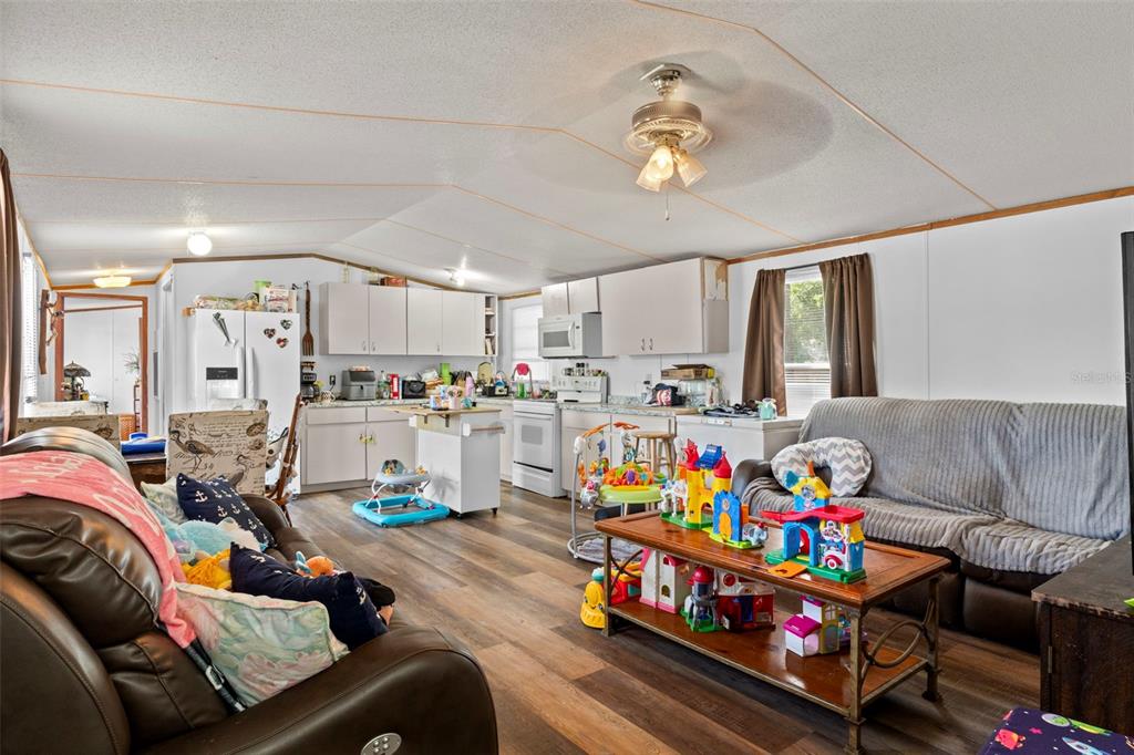 An open-concept living room and kitchen with wood-look flooring and a central ceiling fan — 3474 S ARUNDEL TERRACE, HOMOSASSA, FL