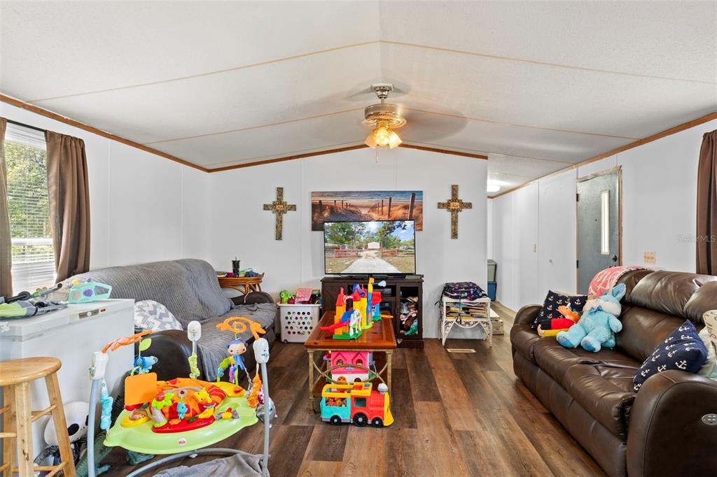 A living room features wood-look flooring, a ceiling fan, and a television on a stand — 3474 S ARUNDEL TERRACE, HOMOSASSA, FL