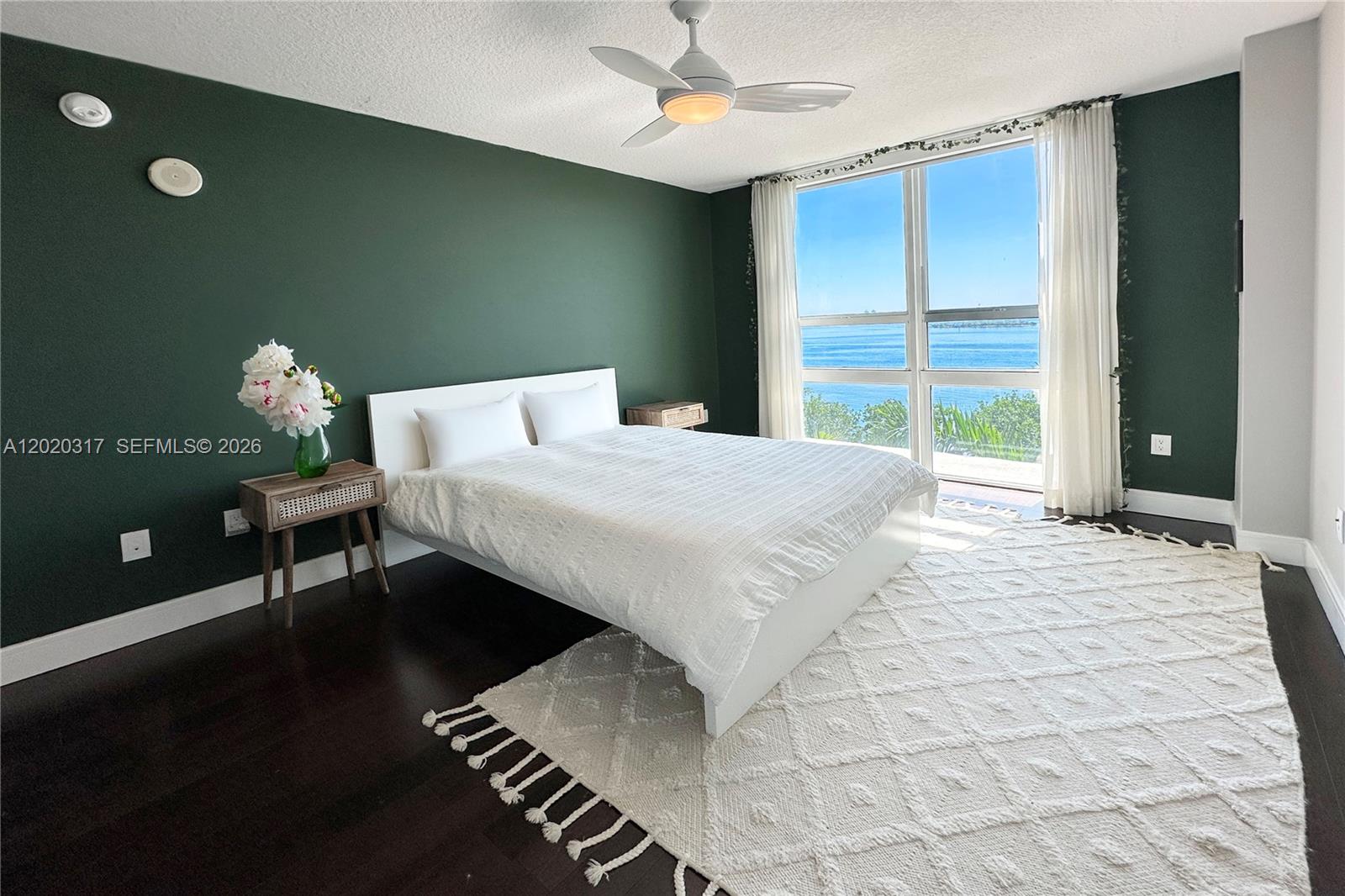 A bedroom with a dark green accent wall, white bed, and a waterfront window view — 2000 N Bayshore Dr # 614, Miami FL 33137, MIAMI, FL