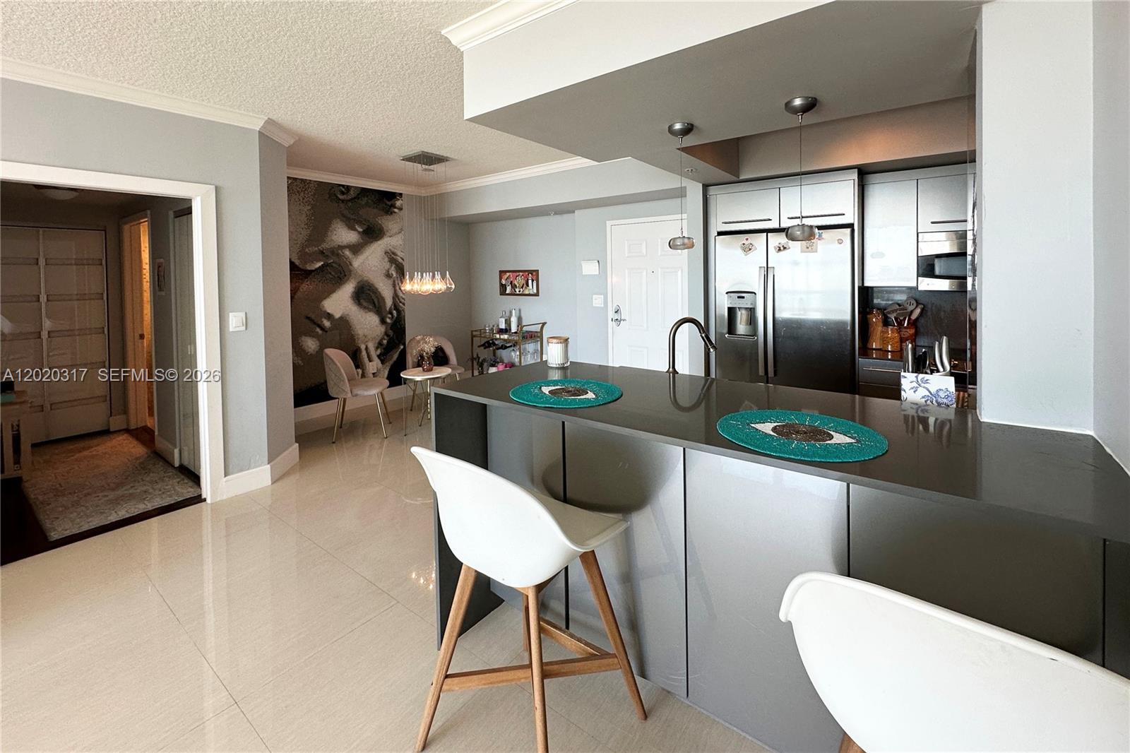 A modern kitchen features a gray island with bar stools and stainless steel appliances — 2000 N Bayshore Dr # 614, Miami FL 33137, MIAMI, FL