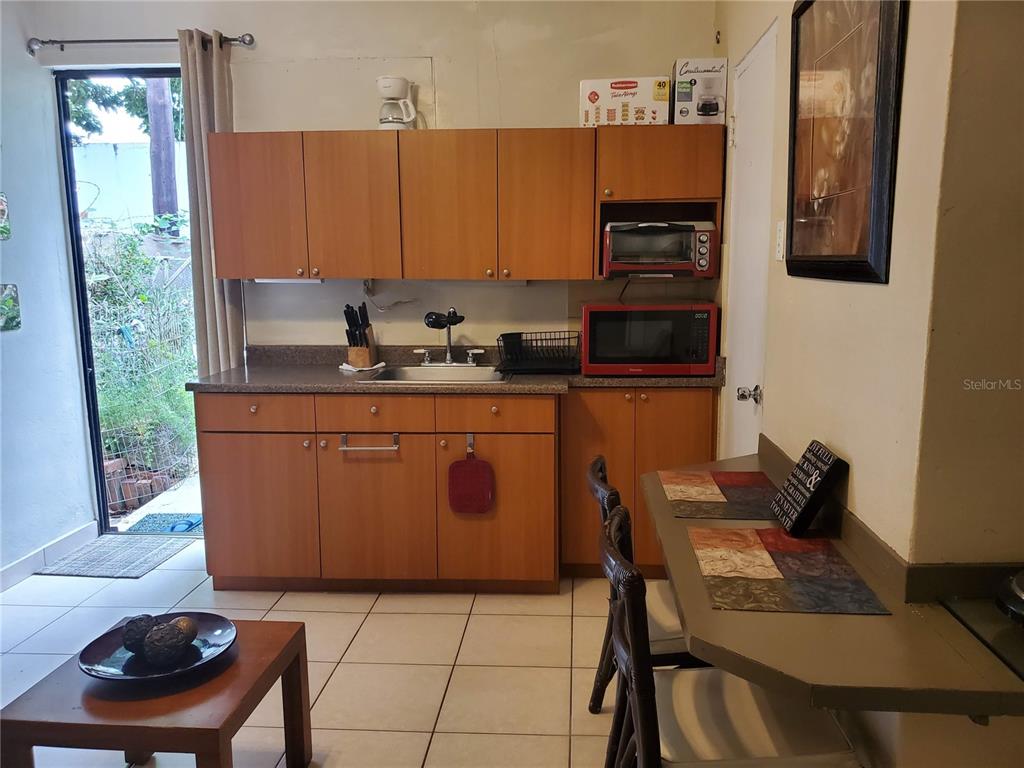 A small kitchen features wood cabinets, a red microwave, and a dining table with chairs — 7 GUERRERO NOBLE UNIT 3, SAN JUAN, PR