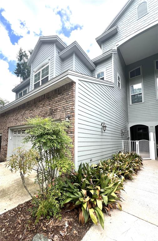 A light blue house features a brick facade, a garage, and a landscaped front yard — 1762 NW 34TH STREET UNIT 2, GAINESVILLE, FL