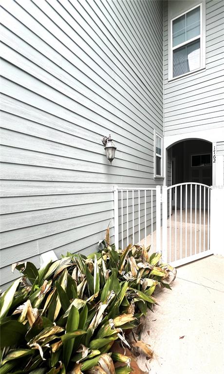 A light-colored siding exterior features a wall-mounted lantern, a white gate, and green plants — 1762 NW 34TH STREET UNIT 2, GAINESVILLE, FL