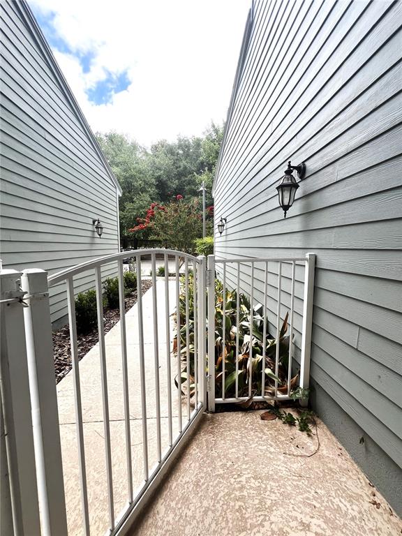 A white metal gate opens to a concrete walkway between two light-colored siding buildings — 1762 NW 34TH STREET UNIT 2, GAINESVILLE, FL