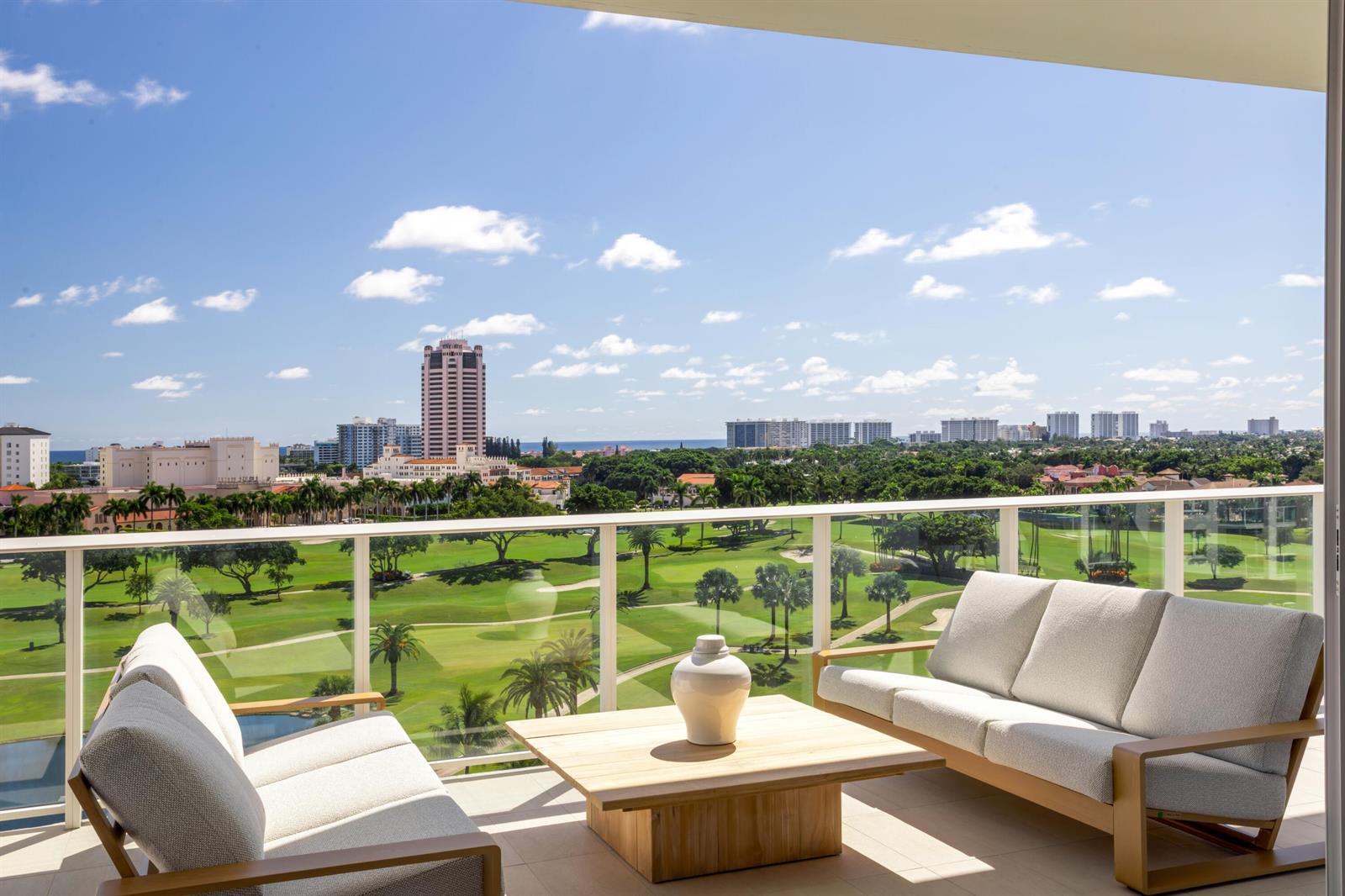A balcony with outdoor furniture overlooks a golf course and a city skyline — 220 SE Mizner Boulevard # 24, Boca Raton FL 33432, BOCA RATON, FL