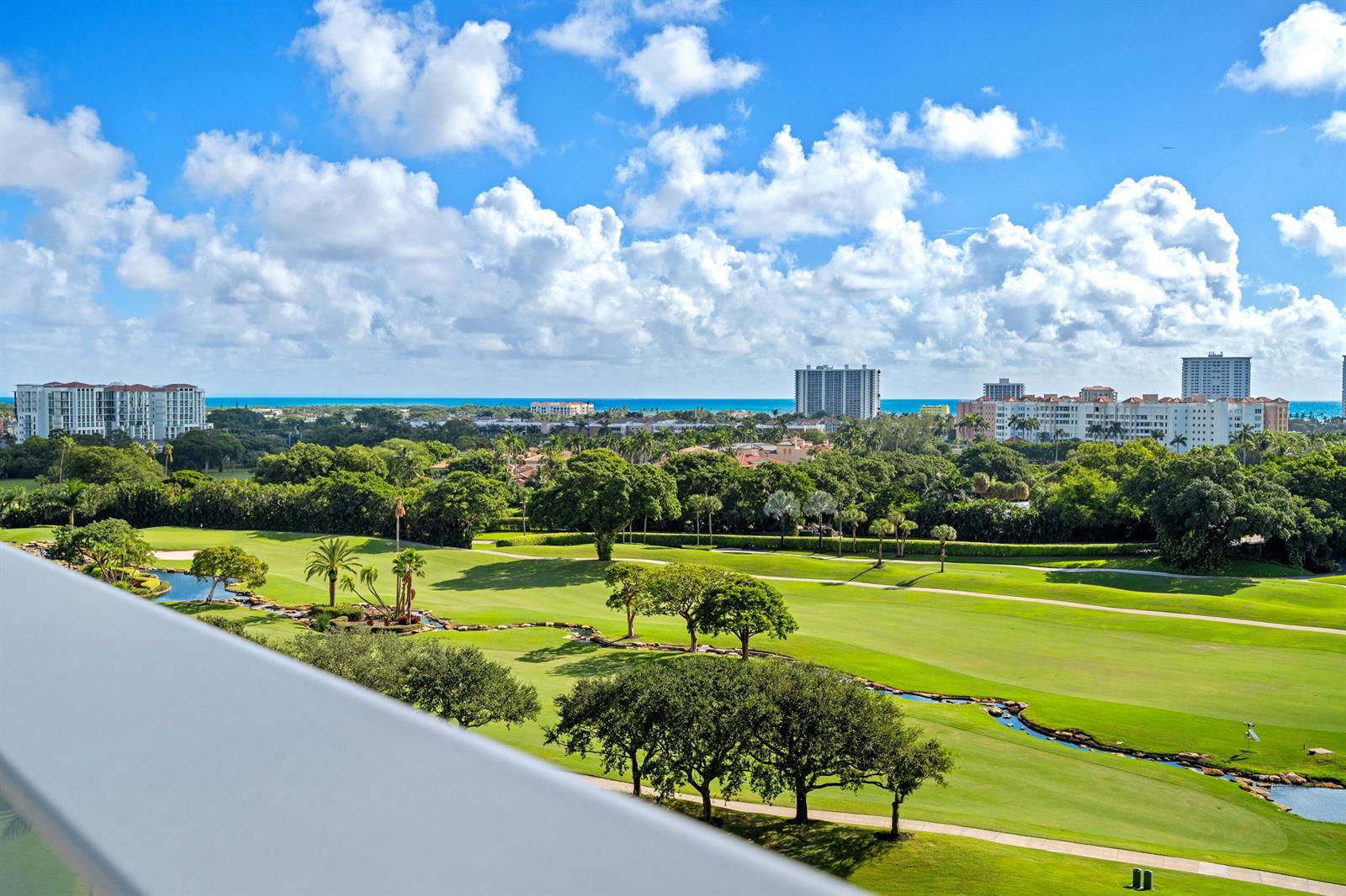 An elevated view of a golf course with lush trees and distant oceanfront buildings — 220 SE Mizner Boulevard # 24, Boca Raton FL 33432, BOCA RATON, FL