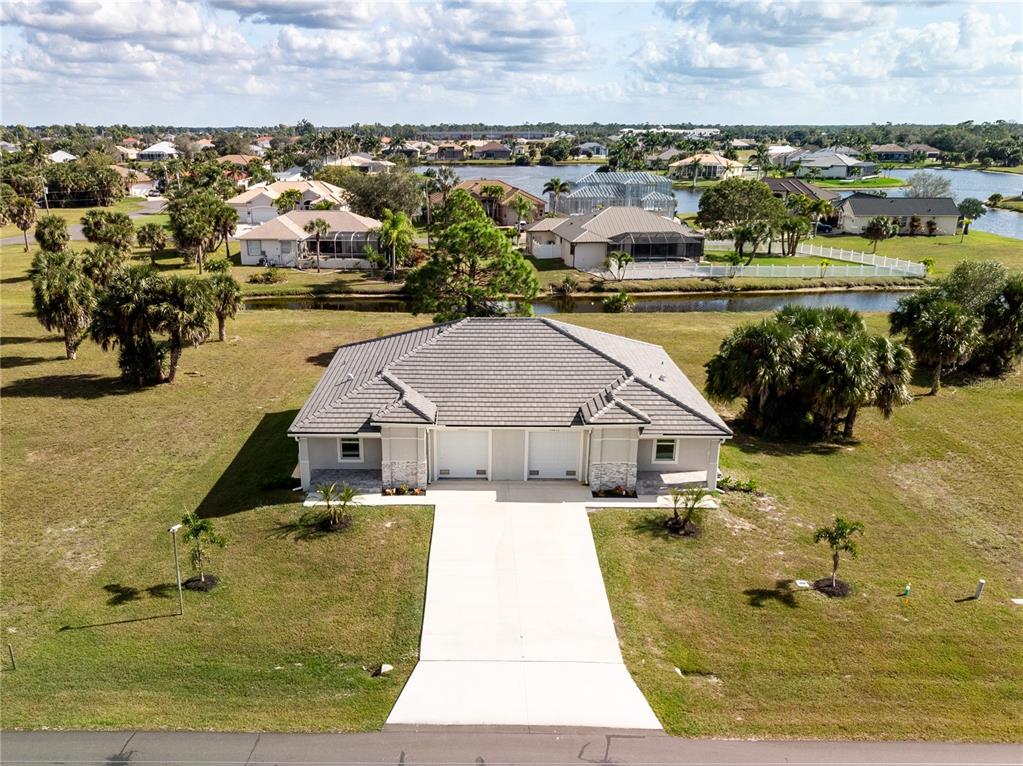 An aerial view shows a single-story duplex with a gray tile roof and concrete driveway — 16810/16812 SAN EDMUNDO ROAD, PUNTA GORDA, FL