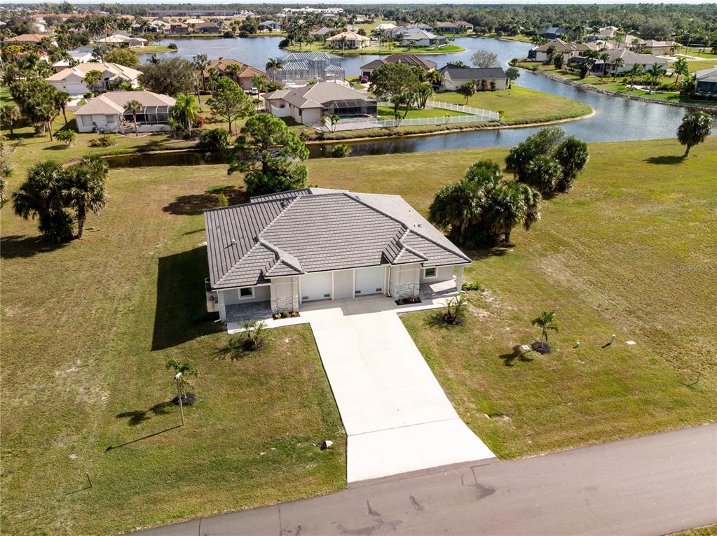 An aerial view shows a single-story house with a gray tile roof and concrete driveway — 16810/16812 SAN EDMUNDO ROAD, PUNTA GORDA, FL