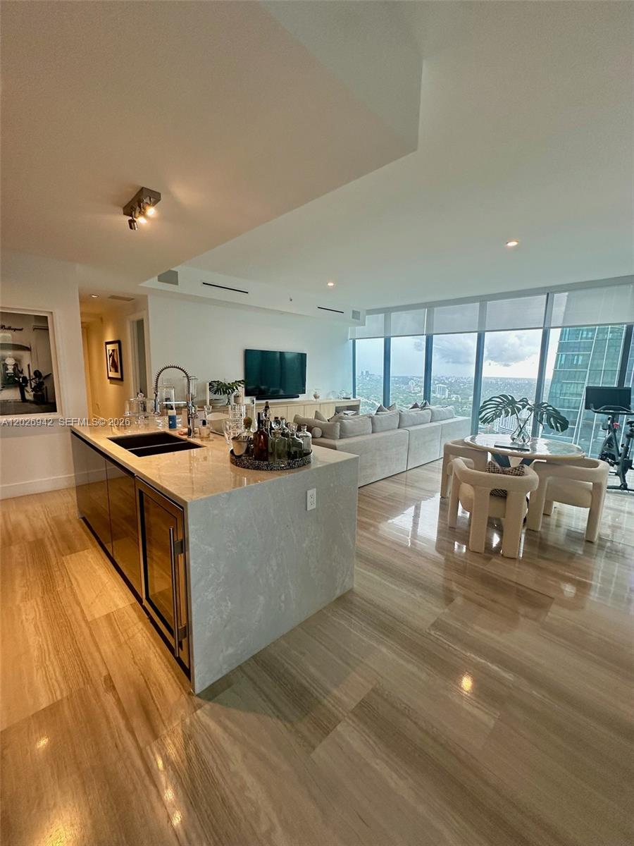 A modern open-concept kitchen and living area features a stone island and floor-to-ceiling windows — 1451 Brickell Ave # 3804, Miami FL 33131, MIAMI, FL