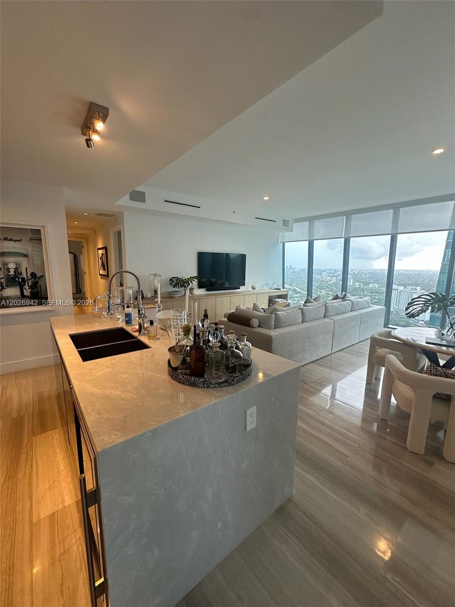 A modern open-concept living area features a stone kitchen island, light flooring, and floor-to-ceiling windows — 1451 Brickell Ave # 3804, Miami FL 33131, MIAMI, FL