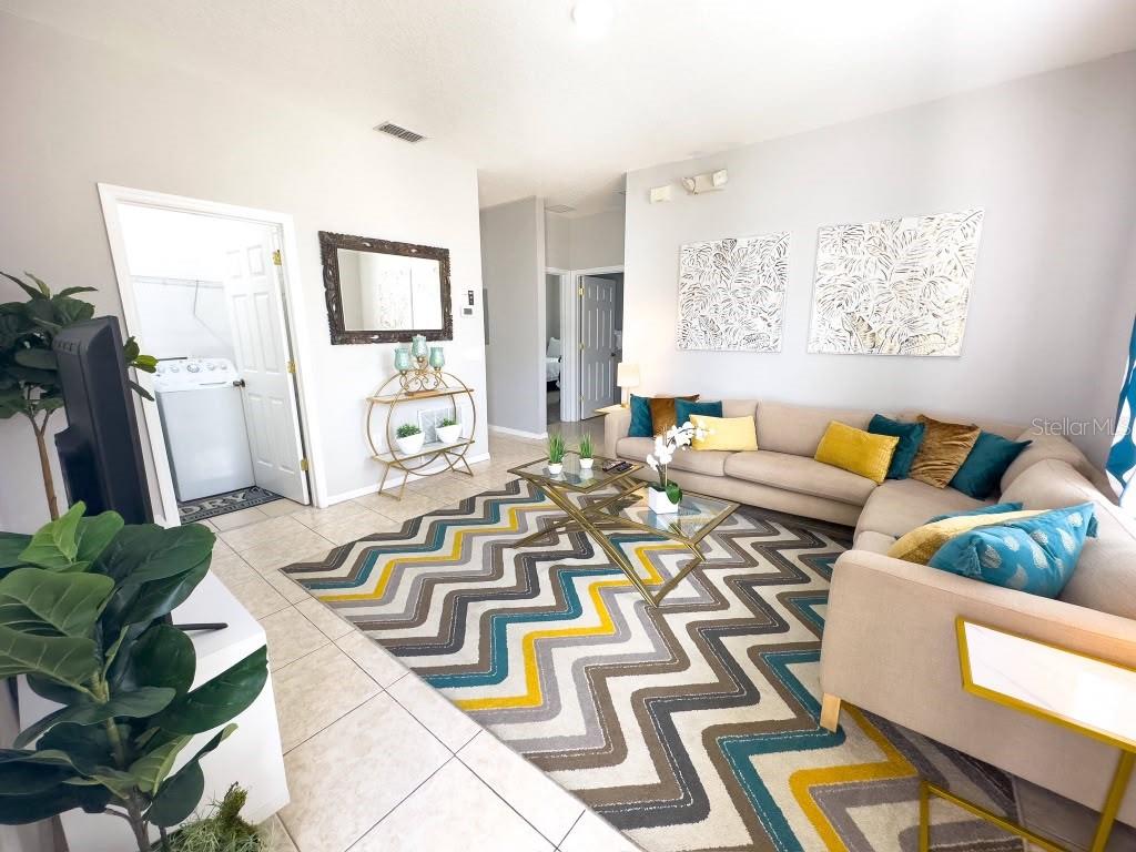 A living room features a beige sectional sofa, a chevron rug, and a laundry closet — 3137 SUN LAKE COURT UNIT A, KISSIMMEE, FL