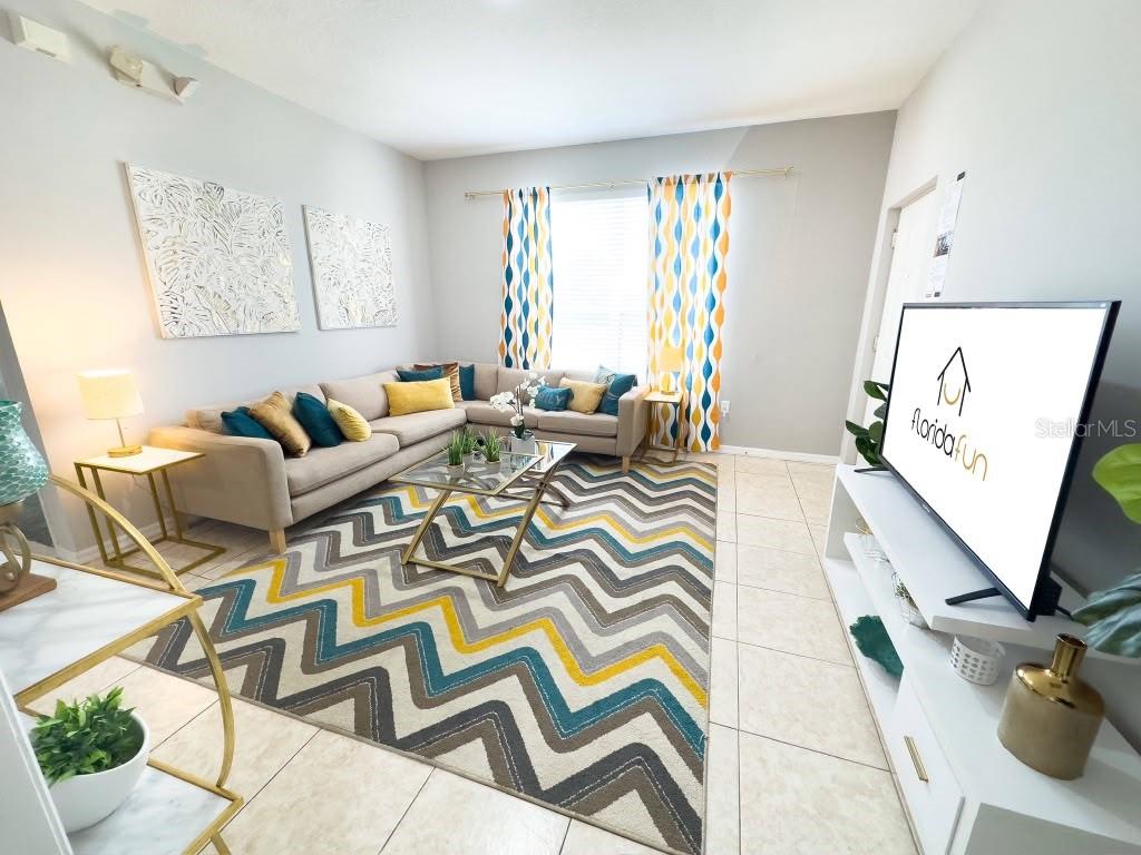 A living room features a sectional sofa, a chevron rug, and a television on a stand — 3137 SUN LAKE COURT UNIT A, KISSIMMEE, FL