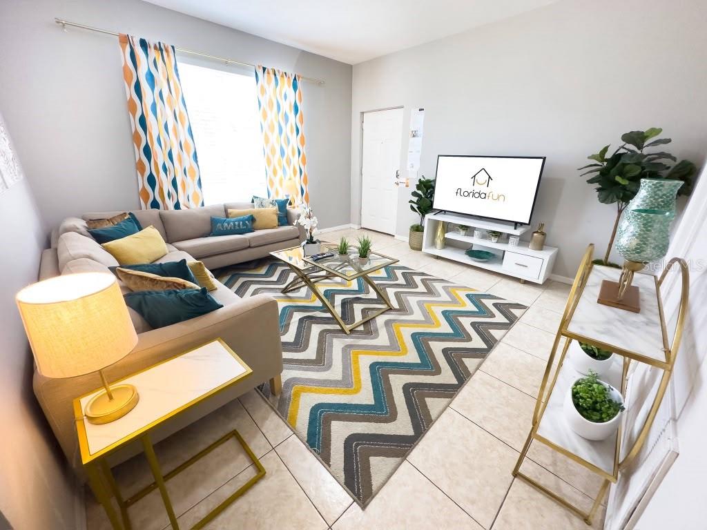 A living room features a sectional sofa, a chevron rug, and a television on a stand — 3137 SUN LAKE COURT UNIT A, KISSIMMEE, FL