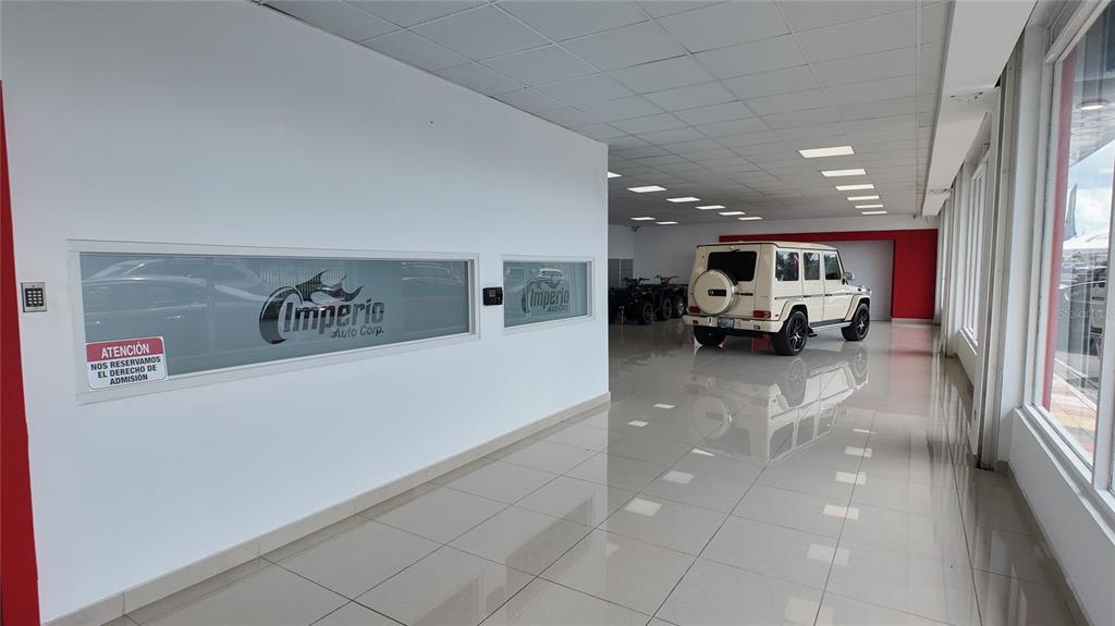 A bright car dealership showroom features a white SUV, tiled floors, and glass-paneled walls — San Agustin AVE 65TH INFANTERIA, SAN JUAN, PR