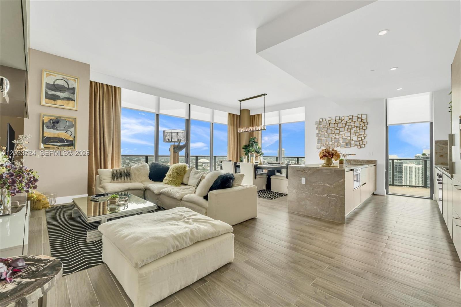 A modern open-concept living area features a kitchen island, dining space, and floor-to-ceiling windows — 1300 S Miami Ave, Miami FL 33130, MIAMI, FL