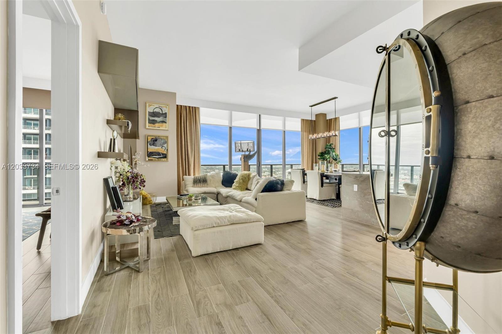 A modern living and dining area features light wood floors, floor-to-ceiling windows, and city views — 1300 S Miami Ave, Miami FL 33130, MIAMI, FL