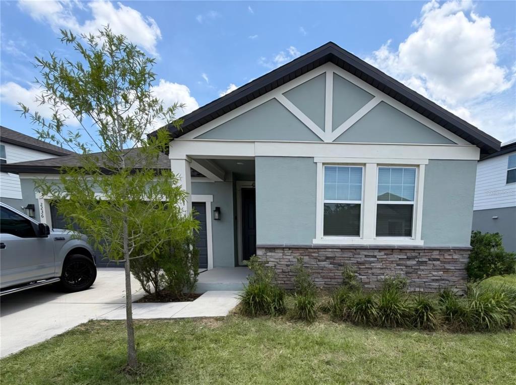 A single-story house with light blue siding, stone veneer, and a front-facing gable roof — 2236 DERWENT DRIVE, DAVENPORT, FL