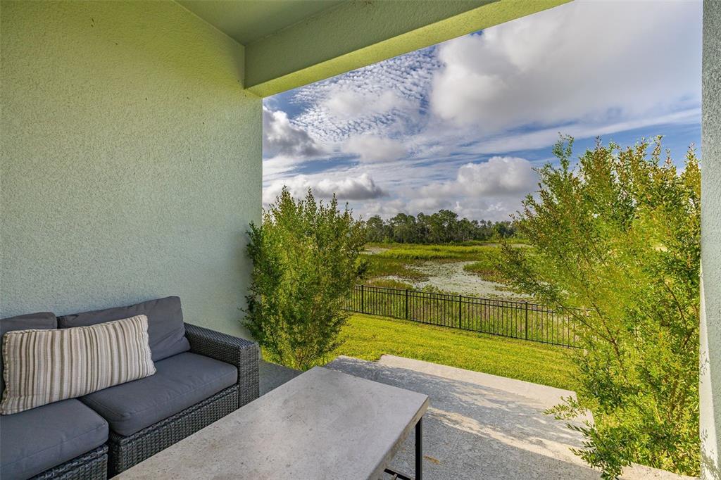A covered patio features a gray sofa and a table overlooking a fenced grassy yard — 2236 DERWENT DRIVE, DAVENPORT, FL