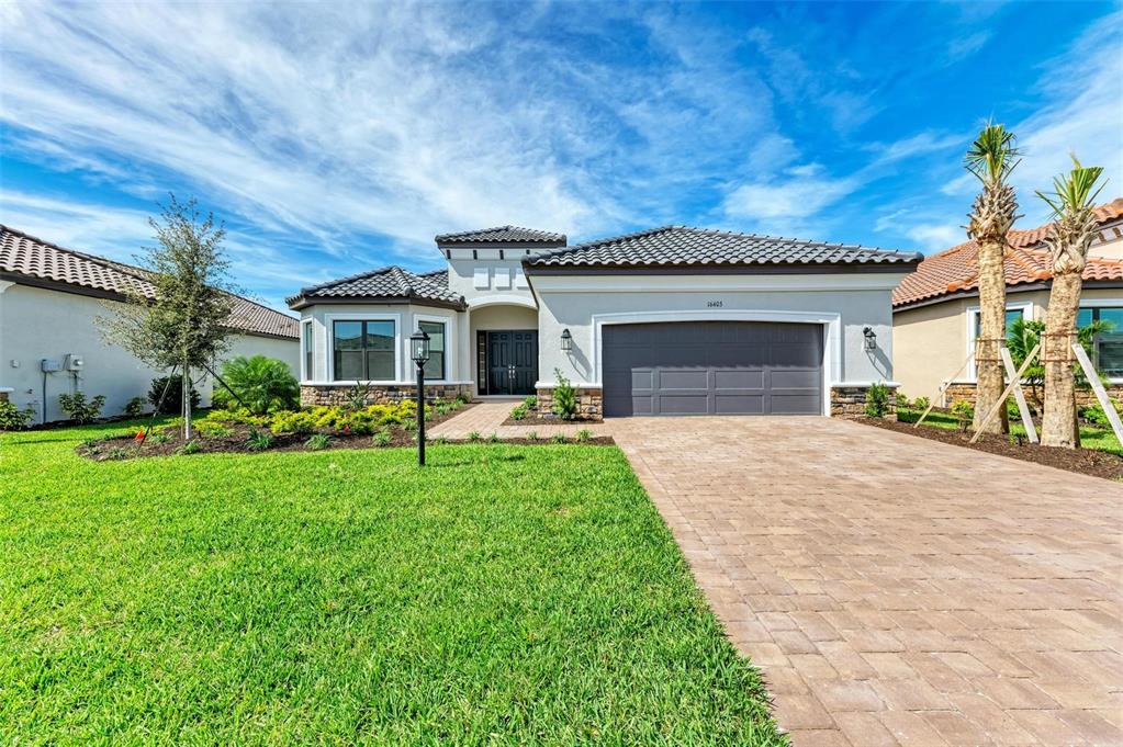 A single-story house with a gray garage, stone accents, and a paved driveway — 16403 UMBRIA PLACE, BRADENTON, FL