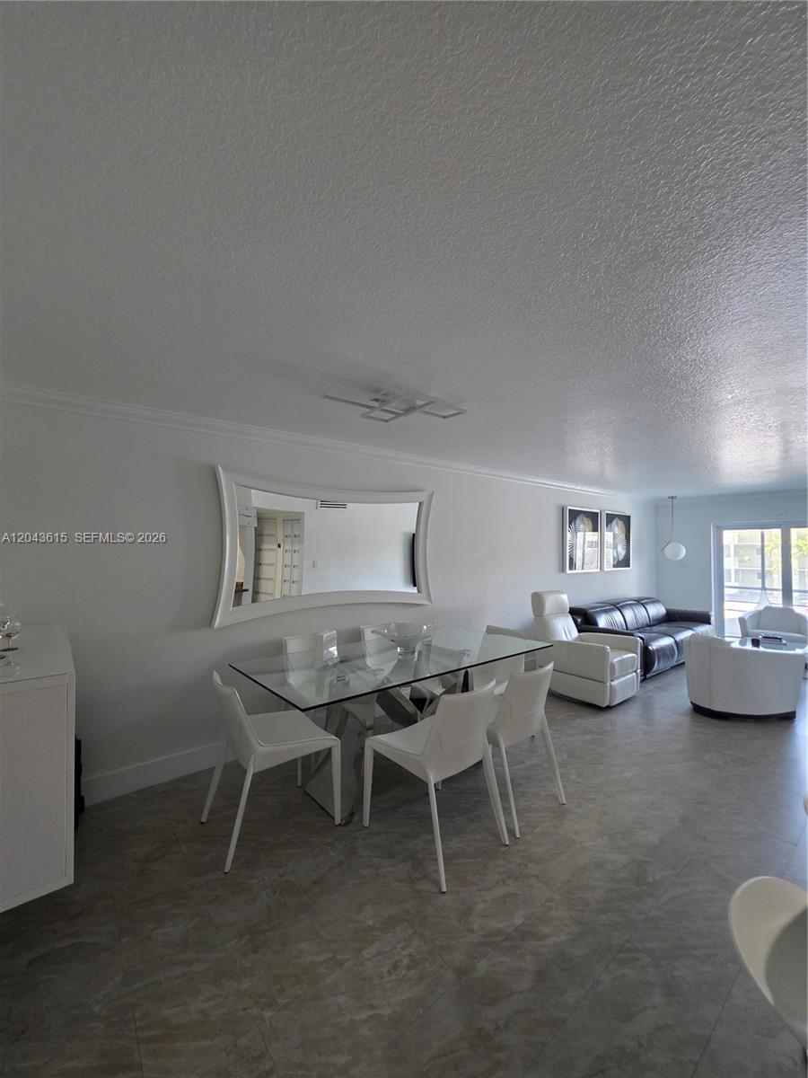 A dining area with a glass table and white chairs sits adjacent to a living room — 4670 W 13th Ln # 206, Hialeah FL 33012, HIALEAH, FL