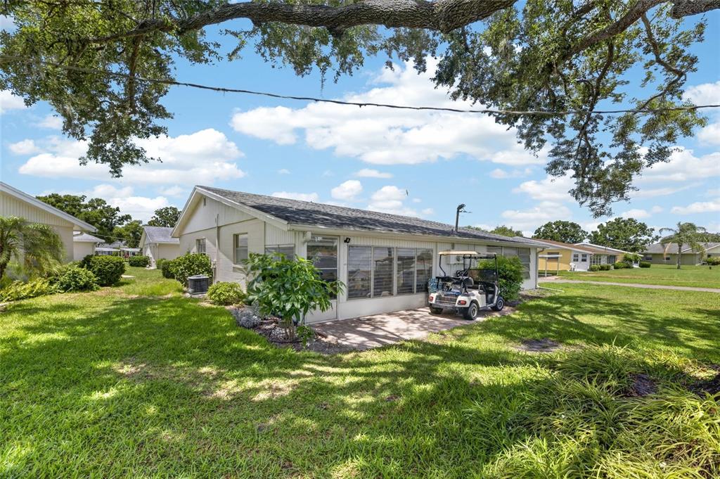 The exterior of a single-story house features a screened-in patio and a parked golf cart — 402 DORCHESTER PLACE UNIT 31, SUN CITY CENTER, FL