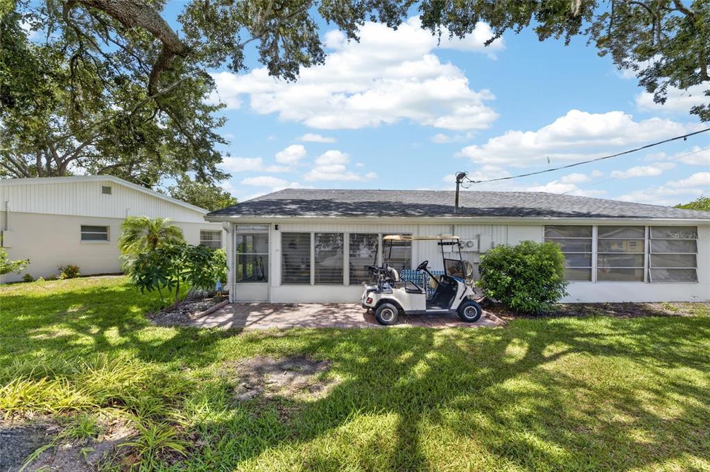 A white house exterior features a paved patio, a golf cart, and a screened-in porch — 402 DORCHESTER PLACE UNIT 31, SUN CITY CENTER, FL