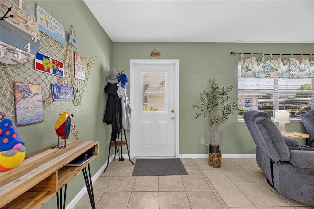 An entryway features sage green walls, tile flooring, a white front door, and coastal decor — 402 DORCHESTER PLACE UNIT 31, SUN CITY CENTER, FL