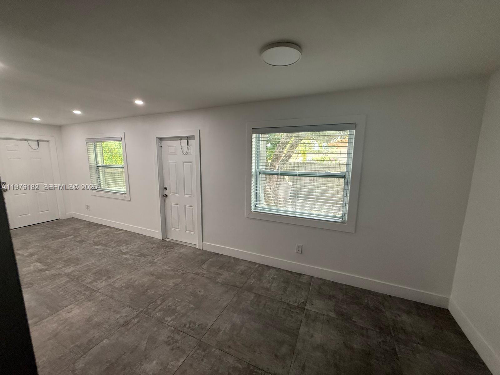 A room with white walls, gray tile flooring, two doors, and two windows with blinds — 11801 SW 180th St, Miami FL 33177, MIAMI, FL