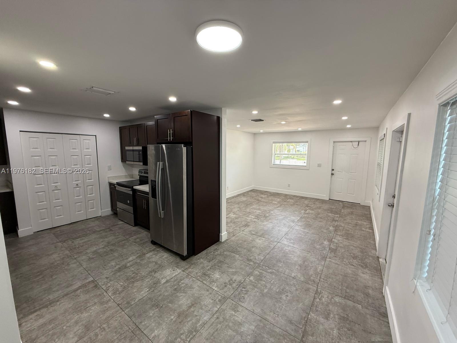 A kitchen with dark cabinets and stainless steel appliances opens into a tiled living area — 11801 SW 180th St, Miami FL 33177, MIAMI, FL