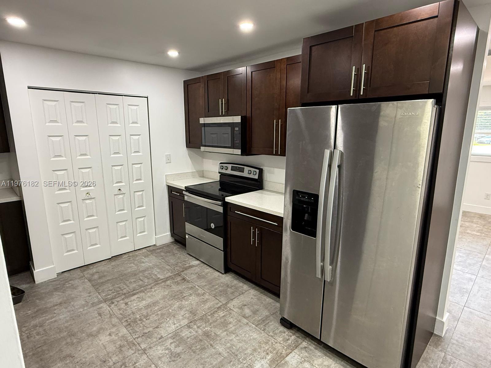 A kitchen features dark wood cabinets, stainless steel appliances, and light-colored countertops — 11801 SW 180th St, Miami FL 33177, MIAMI, FL