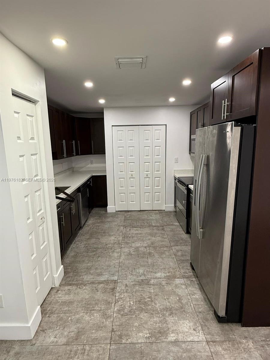 A galley kitchen features dark wood cabinets, stainless steel appliances, and gray tile flooring — 11801 SW 180th St, Miami FL 33177, MIAMI, FL