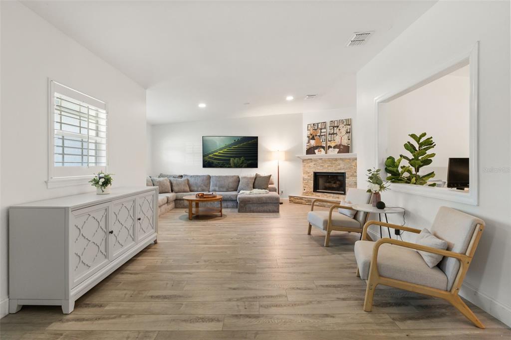 A living room features light wood flooring, a grey sectional sofa, and a stone fireplace — 1871 BARKER DRIVE, WINTER PARK, FL