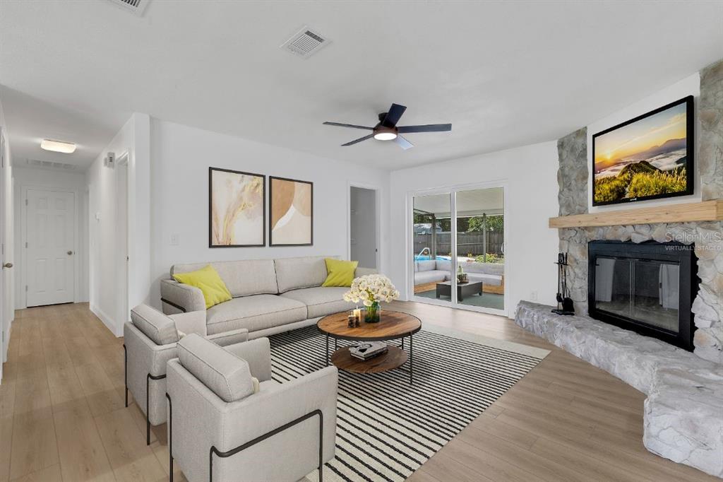 A living room features a stone fireplace, light wood flooring, and a sliding glass door — 3400 SHEPHERD ROAD, MULBERRY, FL