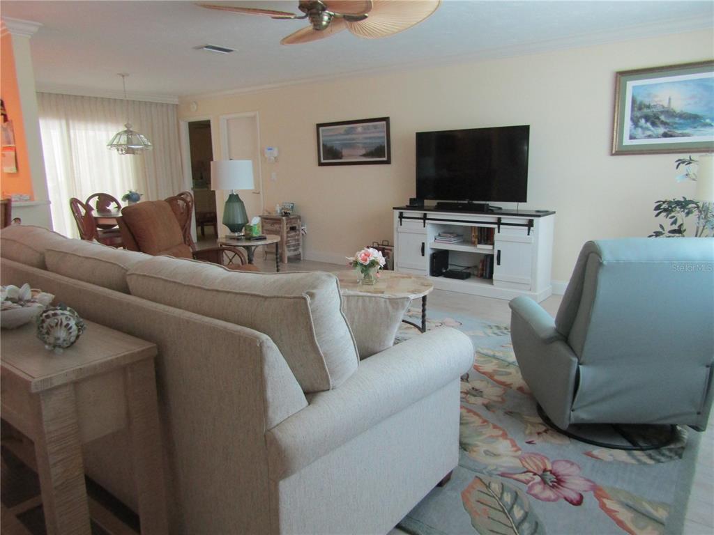A living room features a beige sofa, a light blue armchair, and a white media console — 4700 GREENCROFT ROAD, SARASOTA, FL