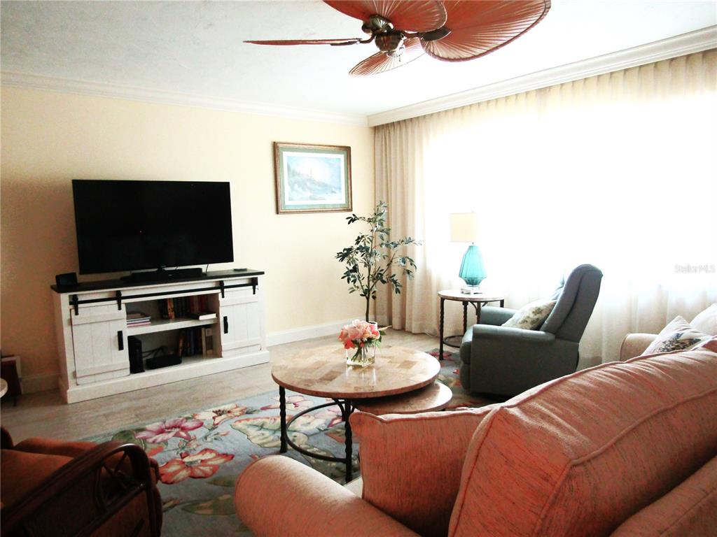 A living room features a television on a white console, a coffee table, and seating — 4700 GREENCROFT ROAD, SARASOTA, FL