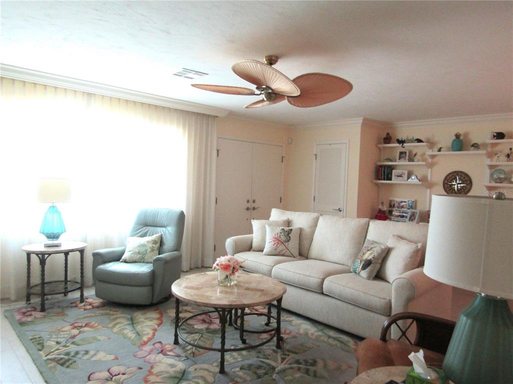 A living room features a beige sofa, a patterned area rug, and a ceiling fan — 4700 GREENCROFT ROAD, SARASOTA, FL