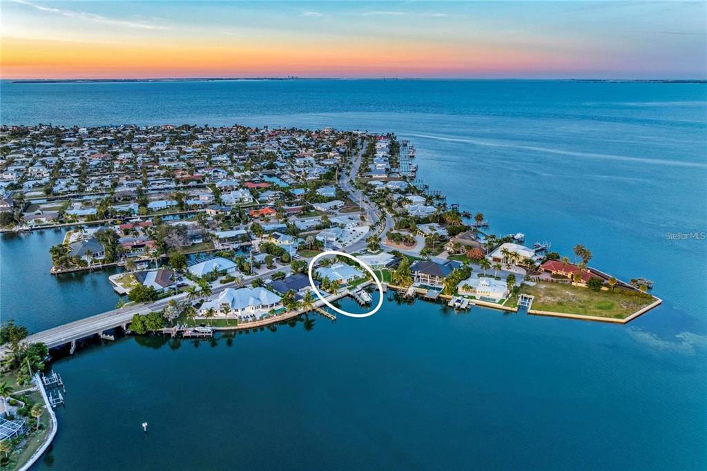 An aerial view shows a waterfront house with a private dock on a coastal peninsula — 605 KEY ROYALE DRIVE, HOLMES BEACH, FL